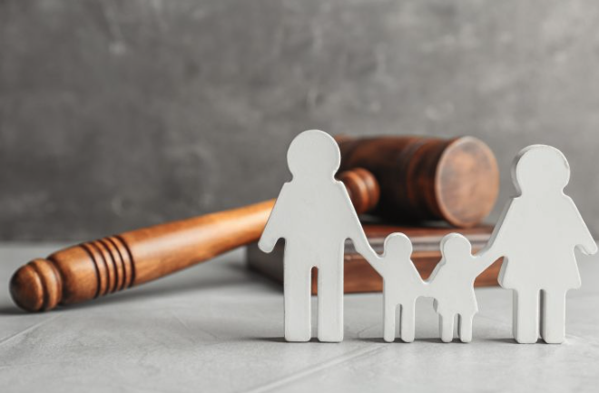 5 Claves legales en Derecho de Familia Elche: mazo de juez sobre mesa con libro de leyes y figuras de madera que representan la unidad familiar.