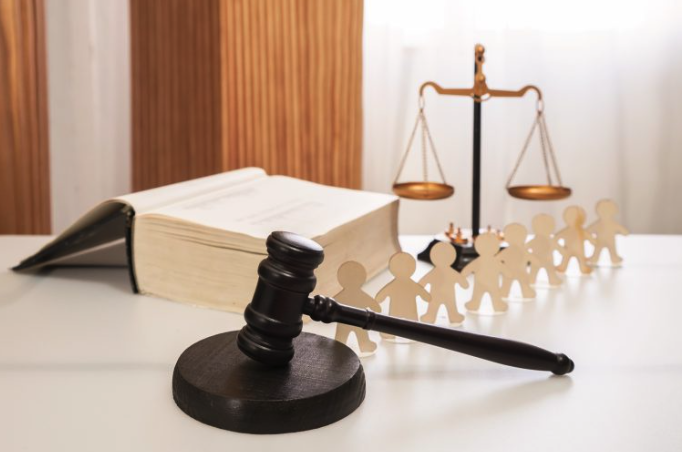 5 Claves legales en Derecho de Familia Águilas: mazo de juez sobre mesa con libro de leyes y figuras de madera que representan la unidad familiar.