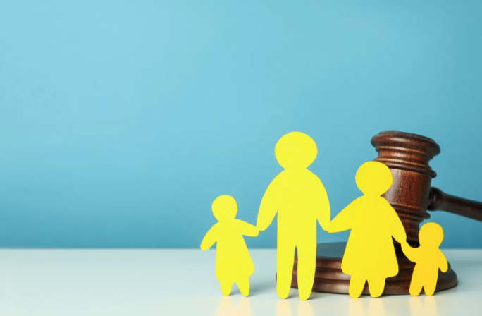 5 Claves legales en Derecho de Familia santa pola: mazo de juez sobre mesa con libro de leyes y figuras de madera que representan la unidad familiar.