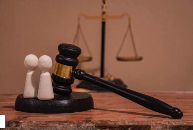 5 Claves legales en Derecho de Familia Benidorm: mazo de juez sobre mesa con libro de leyes y figuras de madera que representan la unidad familiar.